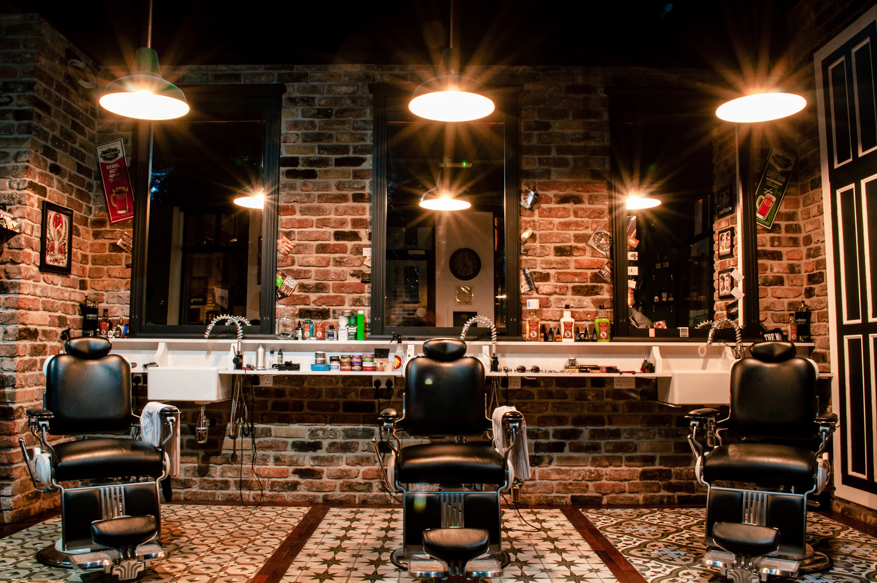 Interno di un barbershop: poltrone in pelle, mattoni a vista e luci calde