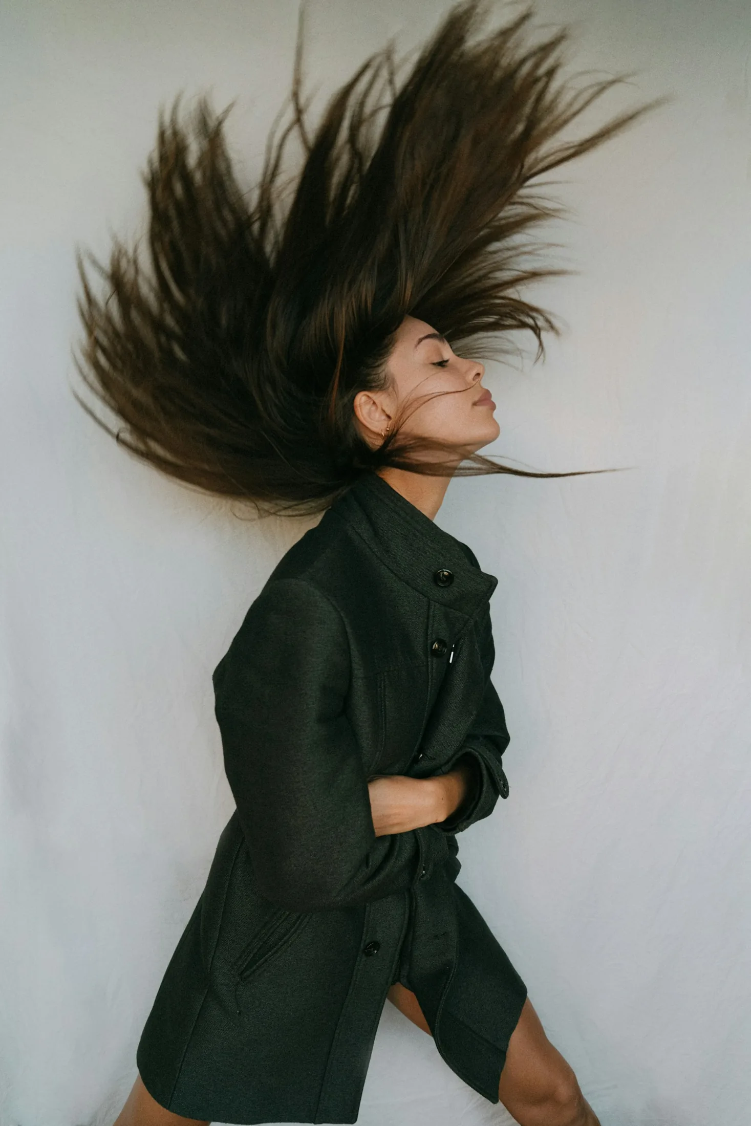 Donna in cappotto nero che tiene i suoi capelli